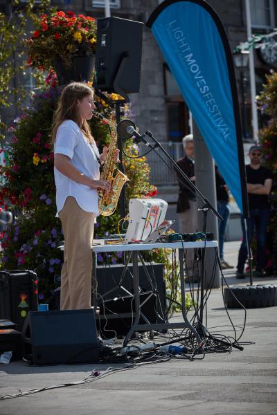 Woman playing a saxophone in front of flowers