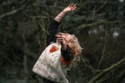 Female dancer with arms in the air in a forest