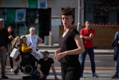 Person dancing in an outsie space, they are in foccus. In the background the audience is out of focus.