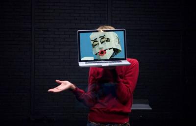 Person with laptop showing a robot's head in front of their face.