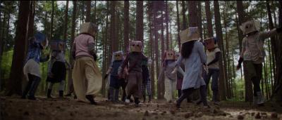 Young people in paper bag masks dancing in the forest.