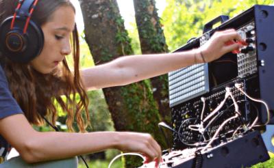 Young girl in the forest with a moduler synthesizer